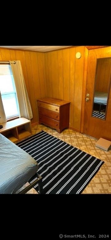 unfurnished bedroom featuring wood walls