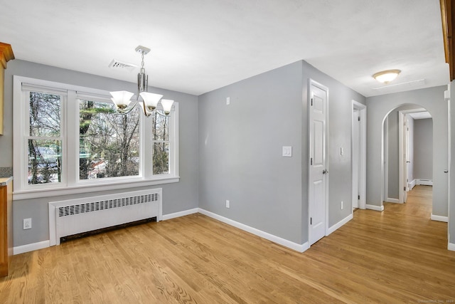 unfurnished dining area featuring a chandelier, radiator heating unit, a baseboard radiator, and light hardwood / wood-style flooring