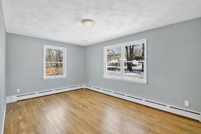 empty room with light hardwood / wood-style floors and a baseboard radiator