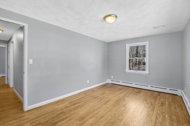 unfurnished room featuring light wood-type flooring and a baseboard heating unit