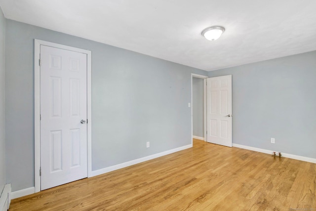 empty room with light hardwood / wood-style flooring and a baseboard heating unit