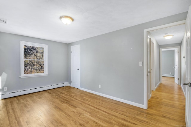 empty room featuring light hardwood / wood-style floors and a baseboard radiator