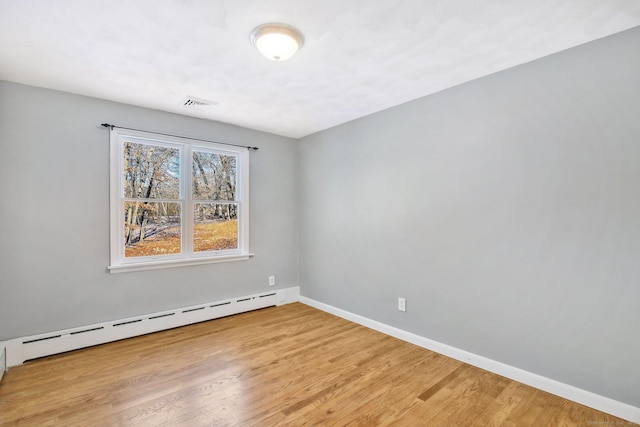 unfurnished room with baseboard heating and light hardwood / wood-style floors