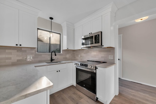 kitchen featuring white cabinets, pendant lighting, stainless steel appliances, and sink