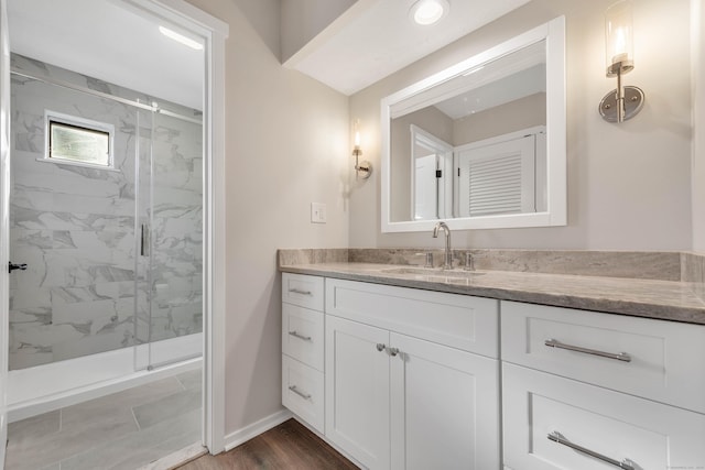 bathroom with vanity, a marble finish shower, baseboards, and wood finished floors