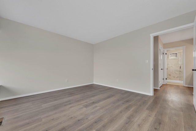 spare room with baseboards, dark wood-style flooring, and visible vents