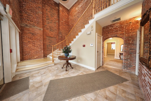 entrance foyer with a towering ceiling and brick wall