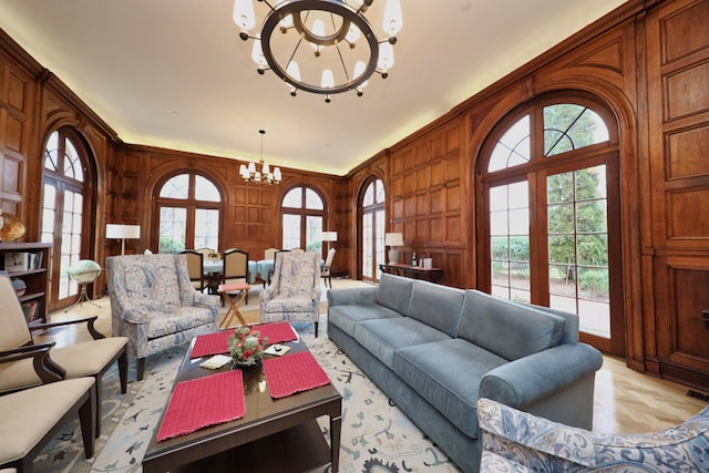 living room with light parquet flooring, wooden walls, and a chandelier