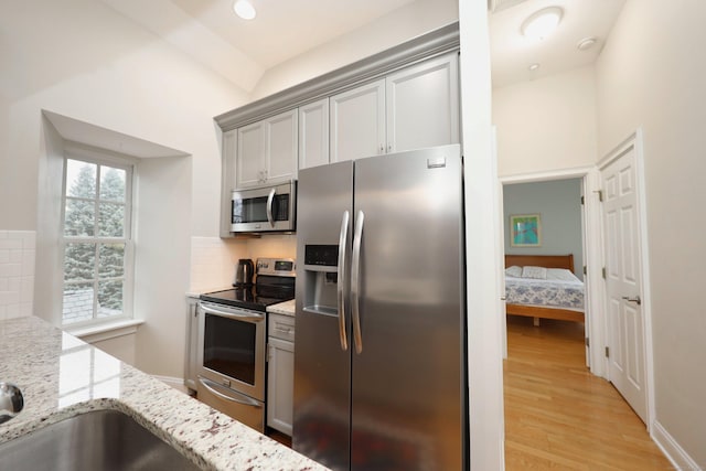 kitchen featuring plenty of natural light, light stone countertops, appliances with stainless steel finishes, and tasteful backsplash