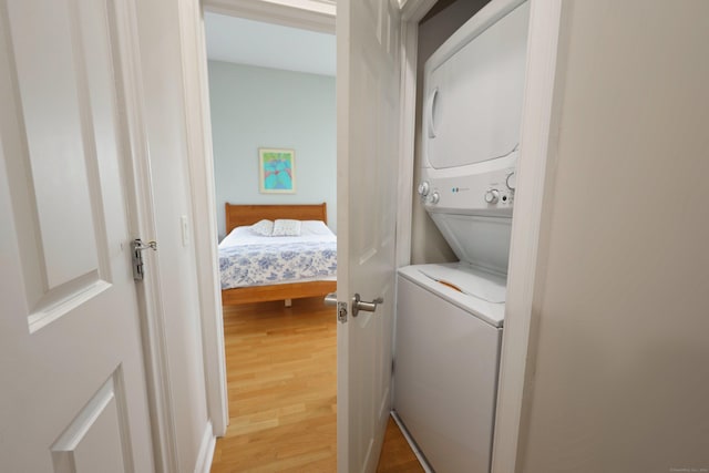 clothes washing area featuring hardwood / wood-style floors and stacked washing maching and dryer