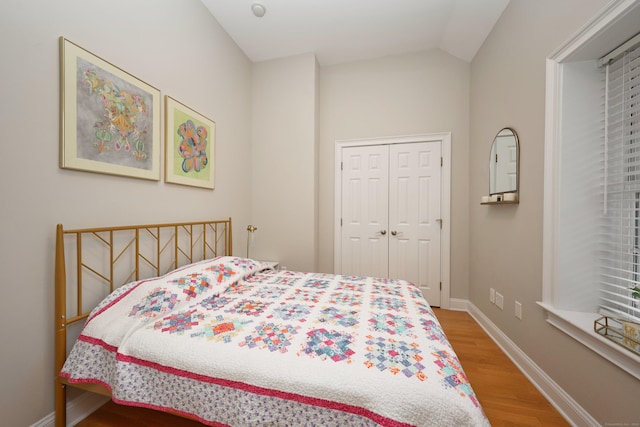 bedroom featuring a closet, lofted ceiling, and light hardwood / wood-style flooring