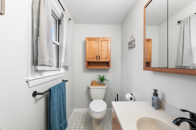 bathroom with tile patterned floors, vanity, toilet, and a wealth of natural light