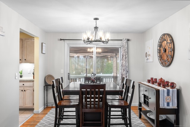 dining area with light hardwood / wood-style floors and a chandelier