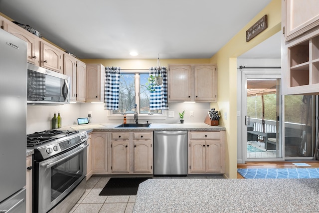 kitchen featuring light brown cabinets, stainless steel appliances, light tile patterned floors, and sink