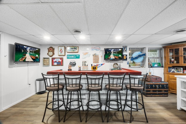 bar featuring a drop ceiling and wood-type flooring