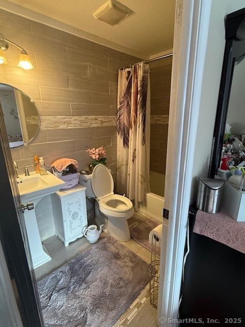 bathroom with shower / bath combo, tile walls, toilet, and tile patterned floors