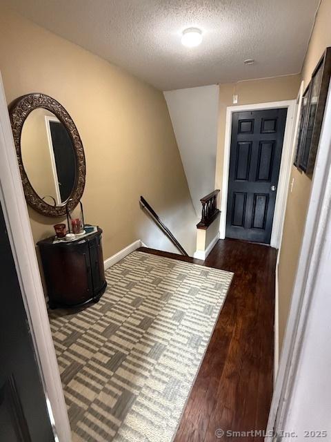 entrance foyer featuring dark wood-style floors, baseboards, and a textured ceiling