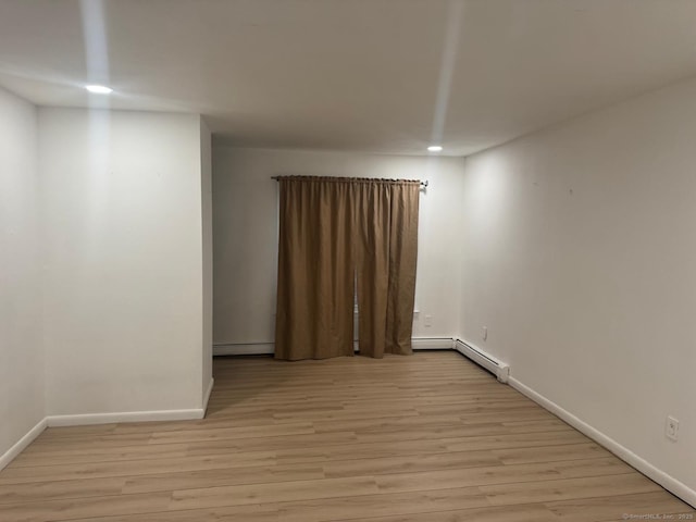 unfurnished room with baseboard heating and light hardwood / wood-style flooring