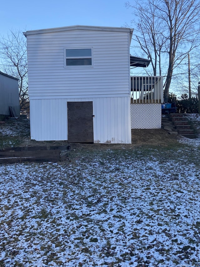 snow covered back of property featuring a sunroom