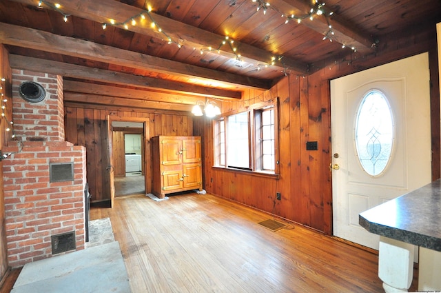 entryway featuring light hardwood / wood-style flooring, wooden ceiling, beamed ceiling, washer / clothes dryer, and wood walls