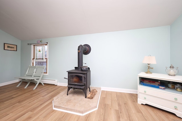 sitting room with light wood-type flooring, a wood stove, and vaulted ceiling