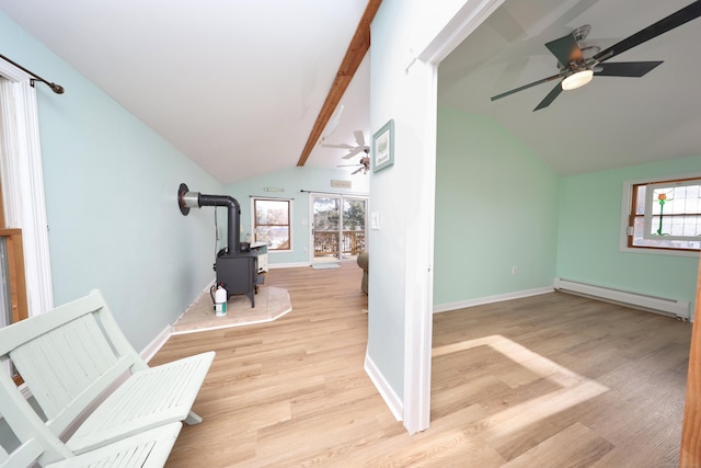 interior space featuring a wood stove, a baseboard radiator, light wood-type flooring, and vaulted ceiling with beams