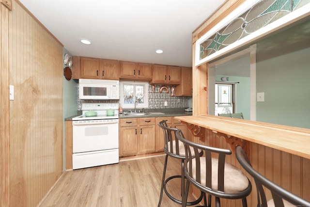 kitchen featuring a healthy amount of sunlight, sink, light hardwood / wood-style floors, and white appliances