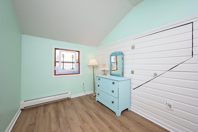 unfurnished bedroom with light wood-type flooring, baseboard heating, and lofted ceiling