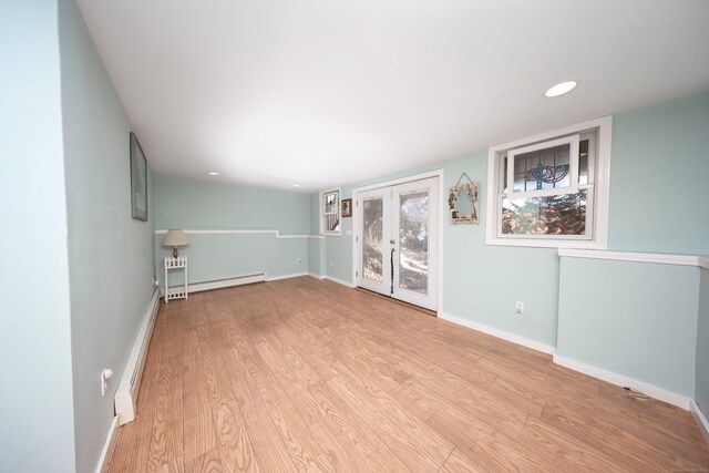 empty room with light wood-type flooring, baseboard heating, and french doors