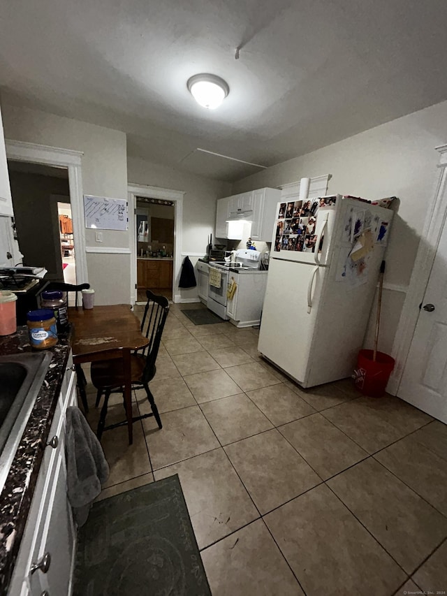 kitchen with light tile patterned floors, white appliances, and white cabinetry