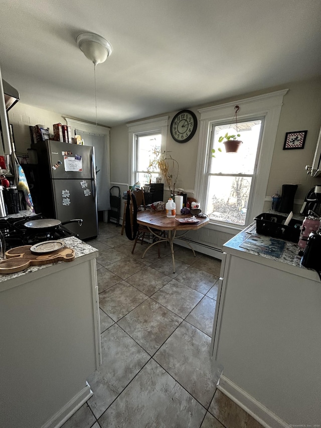 kitchen featuring stainless steel fridge, white cabinetry, and light tile patterned floors