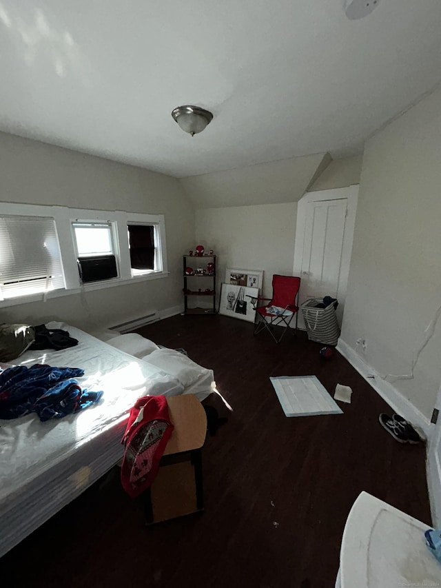 bedroom with dark hardwood / wood-style floors, lofted ceiling, and a baseboard heating unit