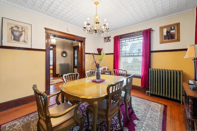 dining room featuring radiator heating unit, dark wood-type flooring, a notable chandelier, and ornamental molding