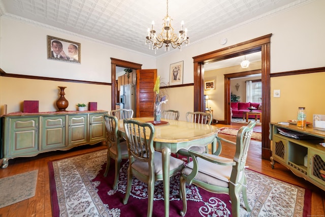 dining room with dark hardwood / wood-style flooring, a chandelier, and ornamental molding