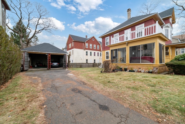 rear view of property with a yard, a balcony, and a carport