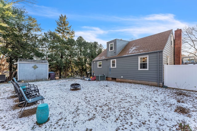 yard covered in snow featuring a storage unit, a fire pit, and central AC unit