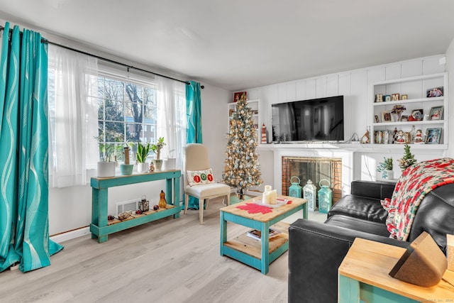 living room with a brick fireplace and light hardwood / wood-style flooring