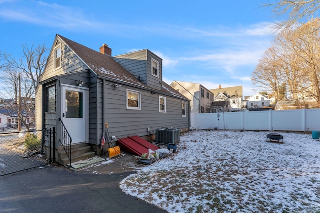 snow covered rear of property with central AC unit