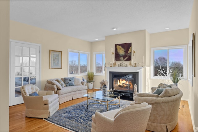 living room with light wood-type flooring, a textured ceiling, and a healthy amount of sunlight