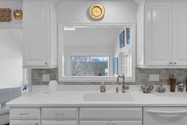 kitchen featuring white cabinetry, stainless steel dishwasher, sink, and backsplash