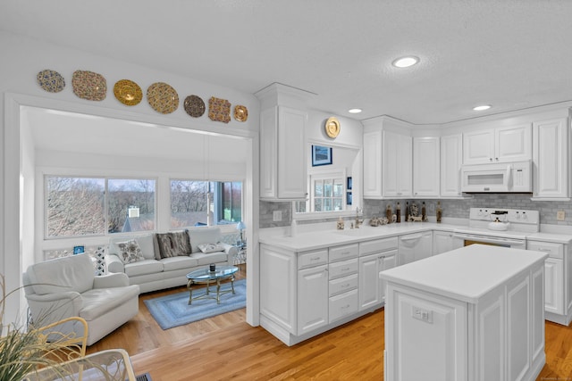 kitchen with white cabinetry, white appliances, a kitchen island, and tasteful backsplash