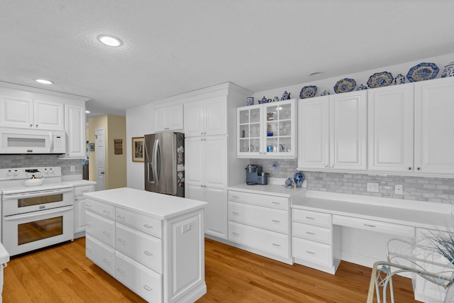 kitchen featuring white appliances, light hardwood / wood-style floors, a center island, and white cabinets