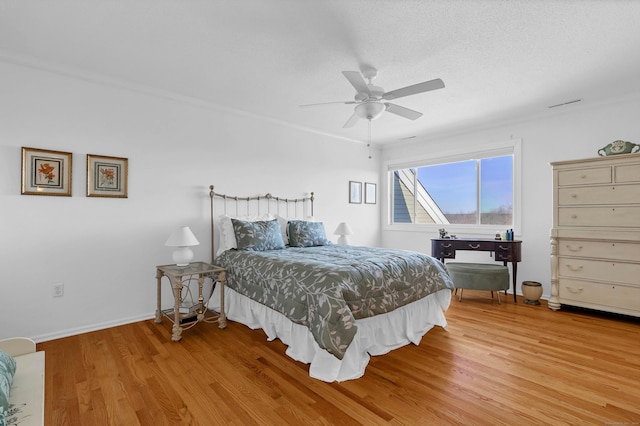 bedroom with hardwood / wood-style floors, a textured ceiling, and ceiling fan