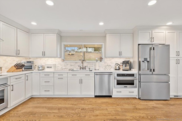 kitchen with stainless steel appliances, white cabinetry, tasteful backsplash, and sink