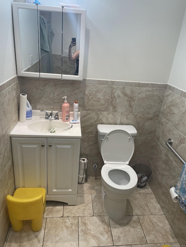 bathroom featuring tile patterned floors, vanity, toilet, and tile walls