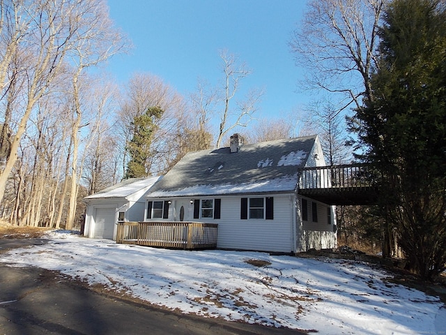 snow covered house with a garage and a deck