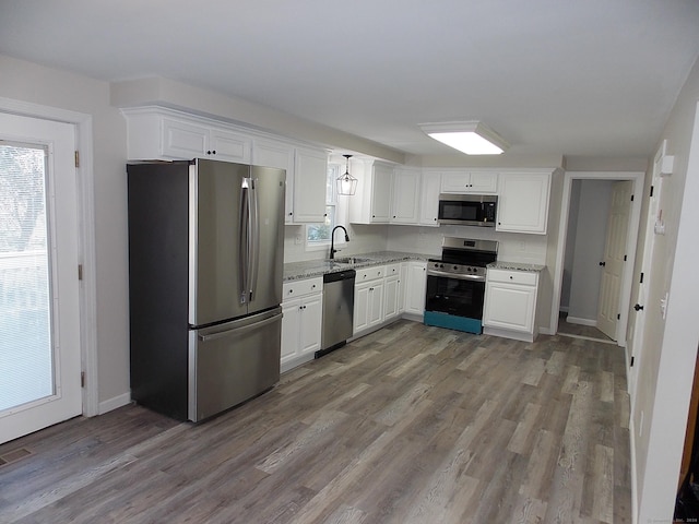 kitchen featuring sink, light hardwood / wood-style flooring, light stone countertops, appliances with stainless steel finishes, and white cabinetry