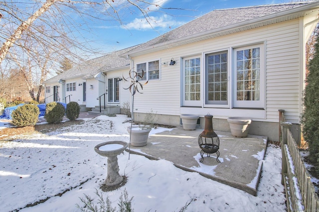 snow covered house featuring a fire pit and a patio area