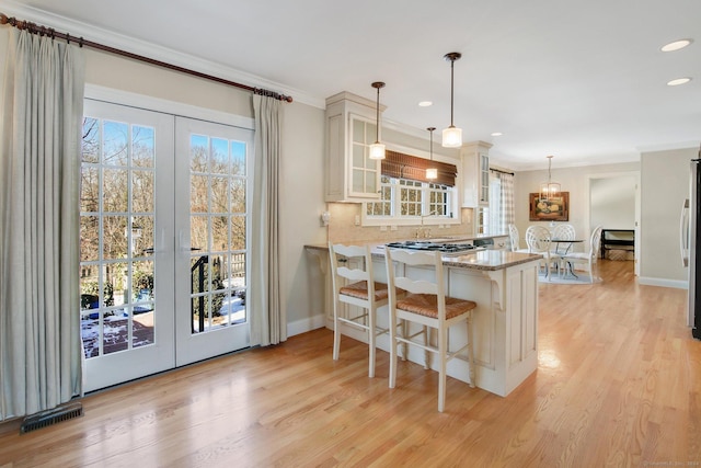 kitchen featuring kitchen peninsula, a breakfast bar, decorative light fixtures, and ornamental molding