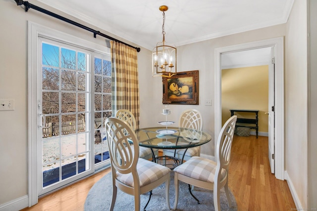 dining space featuring light hardwood / wood-style flooring, ornamental molding, and an inviting chandelier